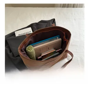Spacious interior of brown suede tote bag holding a tablet, umbrella, and notebook