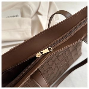 Détail du cabas marron foncé effet crocodile avec fermeture éclair dorée et coutures