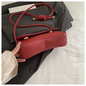 Detail van rode Saffiano leren tas met gouden hardware en verstelbare schouderriem
