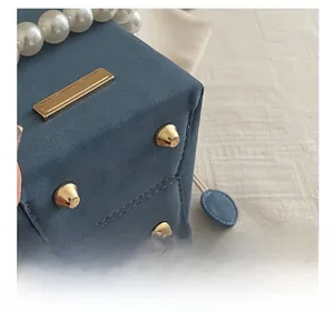 Detail of blue suede crossbody bag showing golden rivets and precise stitching
