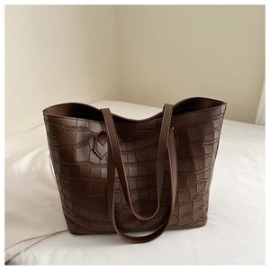 Gros plan du motif crocodile embossé sur le grand sac cabas marron foncé en cuir