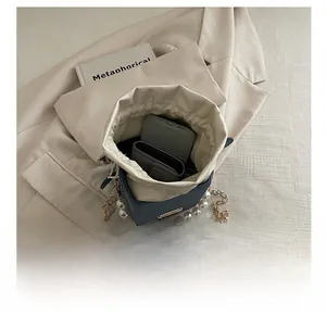 Detail showing the internal capacity of the blue bucket bag with pearl handle and chain