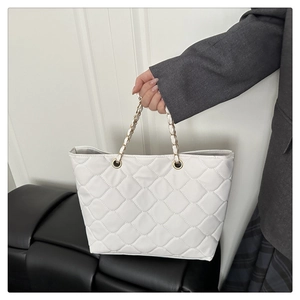 Detail of white quilted tote bag featuring interwoven chain handle and rhombus pattern