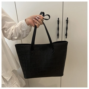 Close-up of black crocodile pattern tote bag with embossed texture and top handles