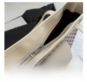 Top detail of tote bag showing smooth silver zipper closure and vintage monogram pattern