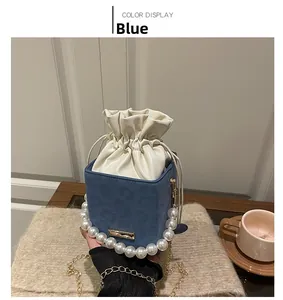 Detail of blue suede bucket bag with decorative pearl handle and gold chain strap