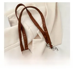 Detail of brown corduroy bag with brown leather handle and silver metal chain decoration