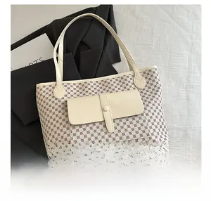 Close-up of a large tote bag with geometric patterns and a leather front pocket detail