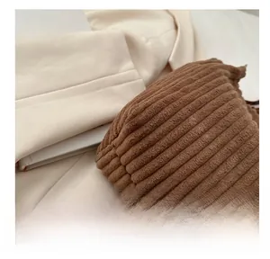 Close-up of brown corduroy tote bag texture paired with a beige blazer and book
