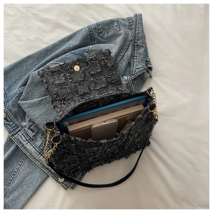 Macro detail of dark grey distressed fabric handbag with chain strap and interior storage