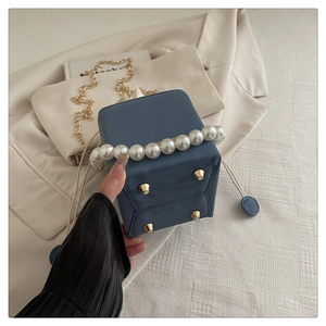 Detail view of the Morandi blue bag with pearl handle and golden protective metal feet