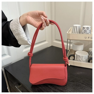 Detailopname van rode Saffiano lederen tas met gebogen bodem en geknoopte schouderriem