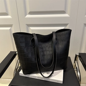 Grand sac cabas noir avec texture crocodile sur un élégant fond d'accessoires blancs