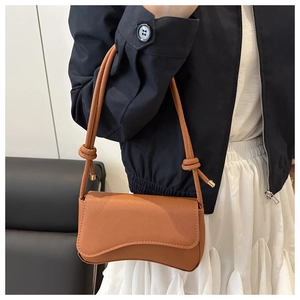 Detailweergave van bruine handtas met golfbasis en geknoopte lederen schouderband details