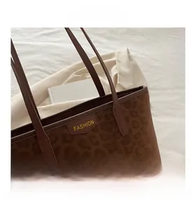 Close-up of leopard print tote bag with brown leather trim and fashion lettering