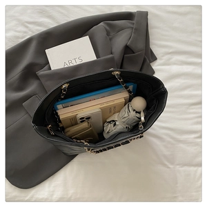 Top view of spacious quilted black tote bag holding a tablet, books, and daily essentials