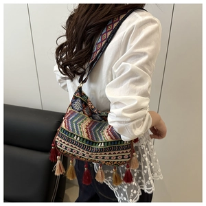 Close-up of bohemian shoulder bag featuring colorful ethnic embroidery and fringe details