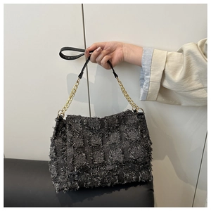 Detail of grey tweed shoulder bag with fringed texture and golden metal chain strap