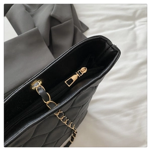 Detailed macro view of the gold metal zipper and quilted leather texture on the tote bag
