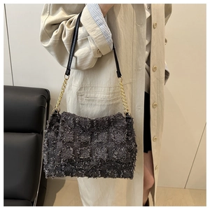 Vue latérale d'un sac à bandoulière en tweed gris avec chaîne dorée porté par un mannequin