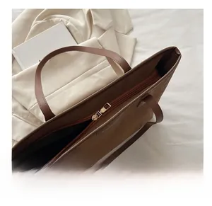 Detail of smooth gold zipper closure on large brown tote bag with fashion text