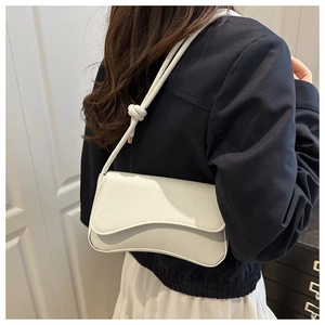 Moderne witte baguette tas met golfslag en geknoopte riem gedragen door een model