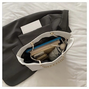 Detailed internal view of spacious white quilted tote bag holding tablets and books