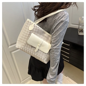 Detail of white monogram tote bag featuring a front pocket and brown geometric patterns