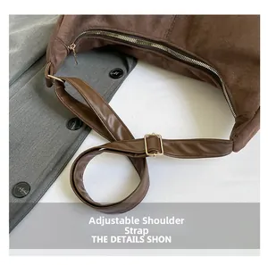 Detail of adjustable leather strap and gold-tone metal hardware on a brown suede tote bag