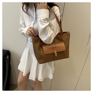 Close-up of brown tote bag with geometric monogram pattern and leather front pocket