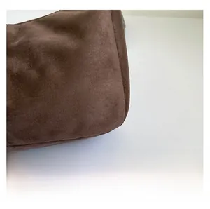 Detailed macro shot of premium matte coffee brown suede fabric on a tote bag