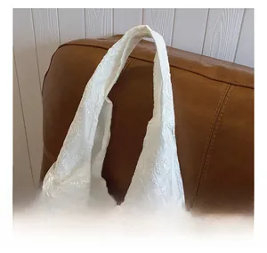 Detail of white floral lace tote bag featuring intricate crochet patterns and handles