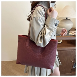 Details der burgunderroten XL-Tote-Bag mit Leopardenmuster an einem Model zu Hause