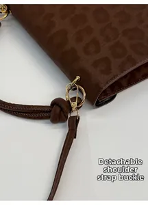 Detail of leopard print handbag featuring gold metal hooks and detachable shoulder strap