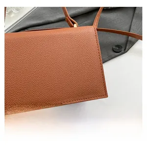 Gros plan sur la texture du cuir marron et les coutures fines du rabat d'un sac