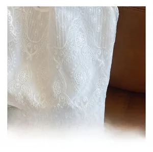 Close-up of white lace fabric featuring intricate floral embroidery and mesh details