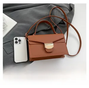 Détail du petit sac en cuir marron avec fermoir métallique doré et texture grainée