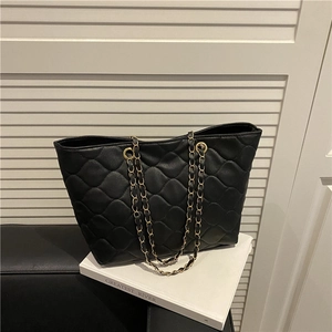 Classic black quilted tote bag with golden chain strap on a minimalist white background