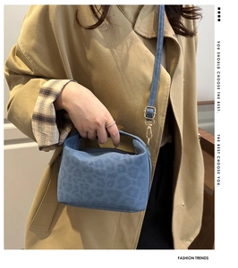 Blue leopard print crossbody bag detail with golden metal clasp on a khaki trench coat