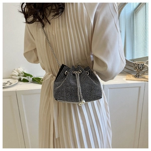 Detail of rhinestone bucket bag with pearl drawstring and silver chain strap on model