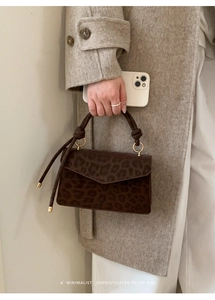 Detailed close-up of retro leopard print handbag with unique knotted handle and gold hardware