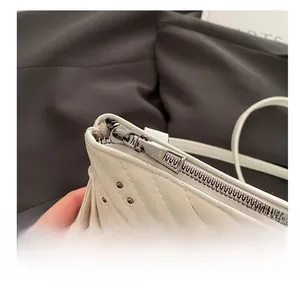 Makroaufnahme von silbernem Reißverschluss und Stepptextur auf weißer PU-Ledertasche