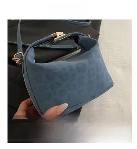 Close-up of blue leopard pattern texture and gold metal clasp on small crossbody bag