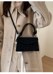 Detail of black leopard print suede bag with gold hardware and knotted handle design