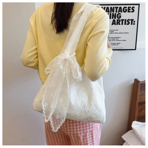 Detailed shot of white floral lace embroidery and a decorative bow on the canvas tote bag