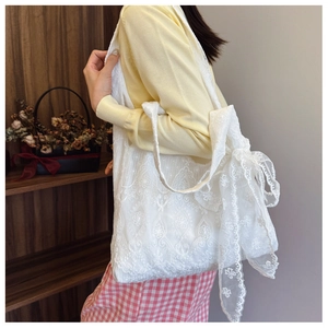Detailed view of white lace tote bag featuring elegant floral embroidery and side bow detail
