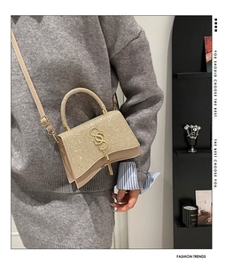 Detail of champagne gold glitter hourglass handbag with S logo and tassel fringe