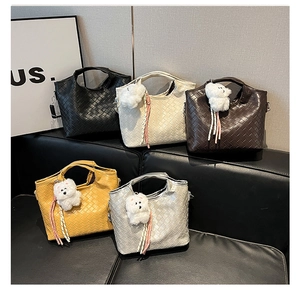 Five woven leather tote bags in various colors on a sofa with bear charms
