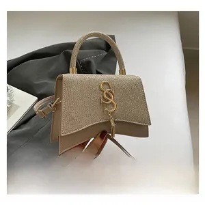 Detail of champagne sequin handbag featuring a gold S-logo and stylish tassel pendant