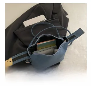 Spacious interior of blue crossbody bag holding a book, phone, and daily essentials